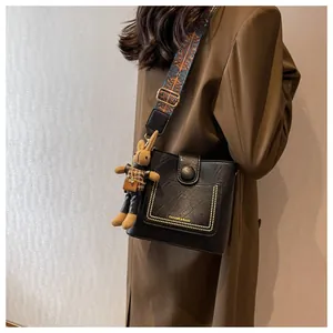 Détail du sac seau noir avec bandoulière tissée et accessoire peluche lapin mignon