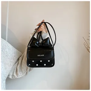 Détail d'un mini sac à main noir avec un grand nœud et motif à pois blancs élégant