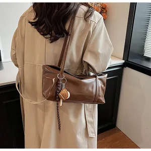 Detail of a brown oil wax leather shoulder bag with clearok logo and burger charm