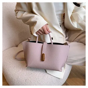 Detail of lavender pebble leather bag with gold oval twist lock on beige background