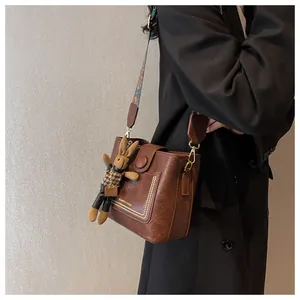 Détail d'un sac seau vintage en cuir marron avec bandoulière ethnique et bijou lapin