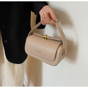 Detailed close-up of a beige leather handbag featuring a golden shell-shaped buckle