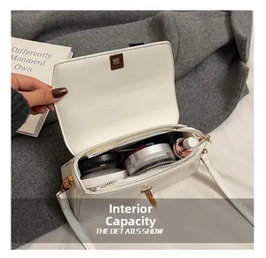 Internal capacity of white square crossbody bag showing cosmetics and golden hardware