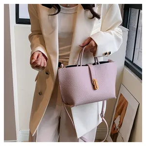 Detail of lavender textured leather tote bag with gold hardware worn with a white suit