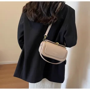 Detail of a beige leather shoulder bag with golden buckle and detachable strap for women