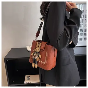 Détail du sac seau en cuir marron avec bandoulière rétro et charmant pendentif lapin
