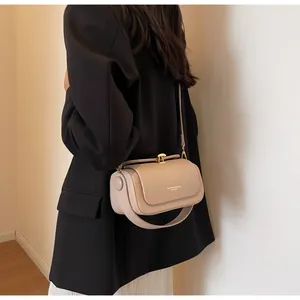 Detailed view of beige leather crossbody bag with fashion print and gold hardware