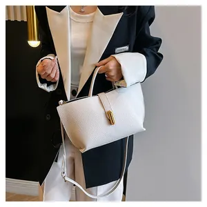 Detailed view of white litchi grain leather tote with gold hardware and shoulder strap
