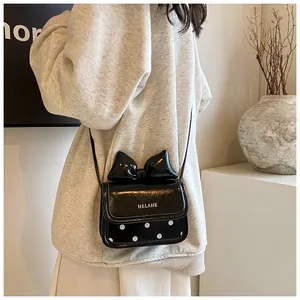 Détail du mini sac bandoulière avec grand nœud et rabat à pois blancs sur cuir noir