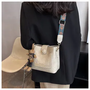 Détail du sac seau blanc cassé avec bandoulière géométrique et breloque lapin