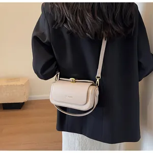 Close-up of beige leather shoulder bag with gold metal buckle and embossed brand lettering