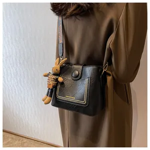 Détail d'un sac seau noir avec clous dorés et bandoulière ethnique aux couleurs vives