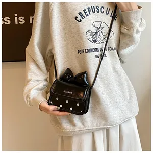 Détail du mini sac bandoulière en cuir verni noir avec nœud et pois blancs