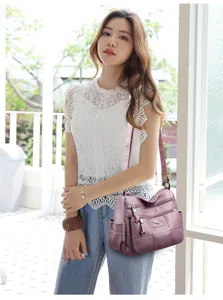 Close-up of purple litchi grain leather bag featuring multiple functional zipper pockets