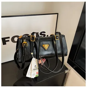 Detailansicht der schwarzen Lackleder-Zylindertasche mit goldenen Metalldetails