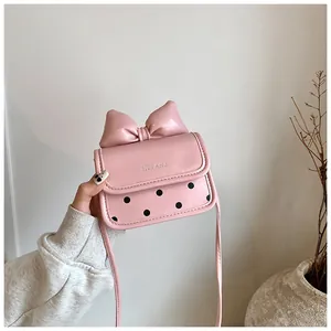 Détail du sac bandoulière en similicuir rose avec grand nœud et motif à pois noirs