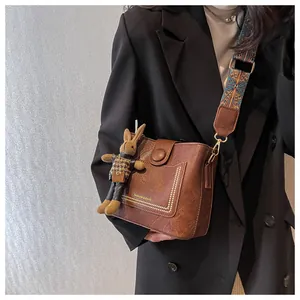Détail du sac seau marron vintage avec bordure cloutée et bandoulière ethnique colorée