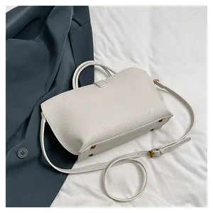 Detail view of off-white tote bag with lychee grain texture and gold bottom studs