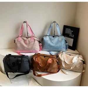 Collection de grands sacs de voyage en cinq couleurs sur un support à plusieurs niveaux