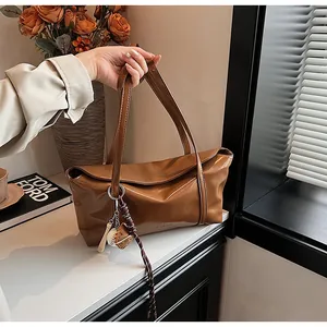Close-up of dark brown oil wax leather tote bag with baseball charm in vintage room