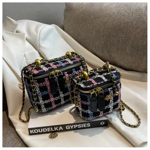 Détail de sacs boîtes en tweed avec zips roses dorés et bandoulières en chaîne