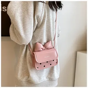 Gros plan du mini sac bandoulière rose avec un grand nœud et des pois noirs