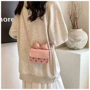 Vue détaillée du mini sac bandoulière en cuir rose avec nœud et motifs à pois noirs
