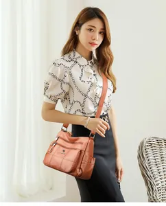 Detail of a brown lychee-pattern faux leather crossbody bag with multiple zip pockets