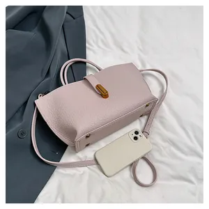Close-up of pink pebbled leather handbag showing size with a smartphone and metal lock