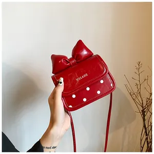 Détail d'un mini sac à bandoulière rouge avec un grand nœud et des pois blancs