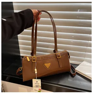Detail einer braunen Leder-Achseltasche mit goldenem Dreieckslogo und Reißverschluss