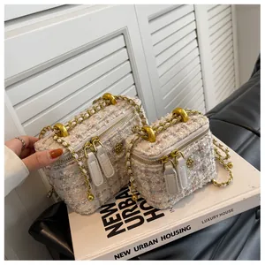 Gros plan de mini sacs box en tweed avec chaîne dorée et détail camélia en deux tailles