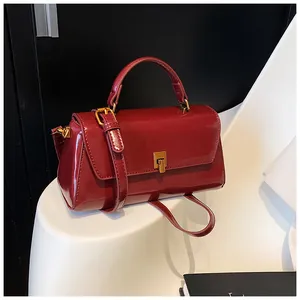 Close-up of wine red patent leather handbag with a gold square twist lock detail