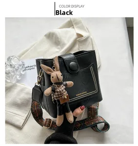Détails du sac seau noir avec rivets dorés, pendentif lapin et bandoulière brodée
