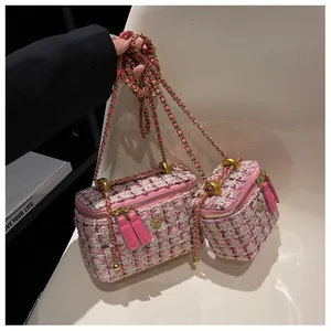 Détail macro du tissu en tweed rose et du fermoir fleur dorée sur le sac à chaîne