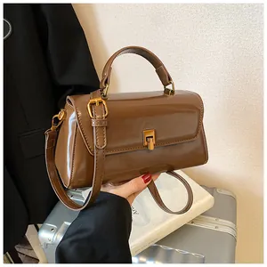 Detailed view of brown patent leather handbag featuring gold clasp and shiny finish