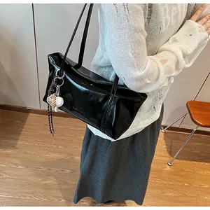 Detail view of glossy black oil wax leather shoulder bag with decorative heart charms