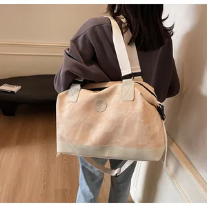 Détail du sac de voyage marbré avec bandoulière réglable et logo circulaire en cuir