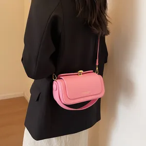 Pink leather crossbody bag with gold buckle on a model wearing a black suit