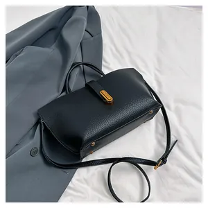 Detail of lychee pattern leather tote bag with gold hardware on a gray suit background