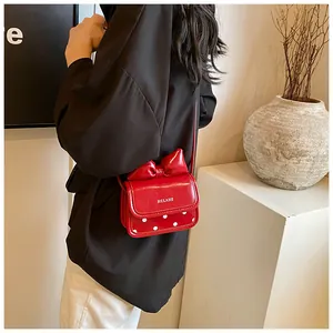 Détail du petit sac rouge à nœud et pois blancs porté par un mannequin