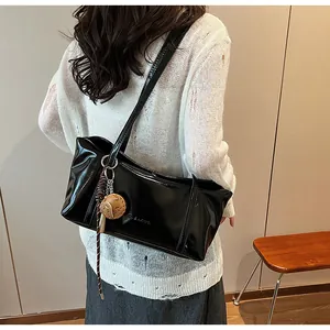 Detail of black glossy wax leather tote bag with Clearxx lettering on a model shoulder