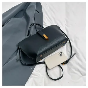 Detail of black lychee grain leather bag with gold buckle and adjustable strap