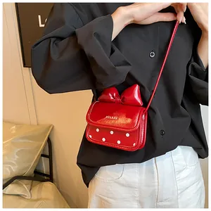 Détail du mini sac bandoulière rouge avec décoration de nœud et motifs à pois blancs