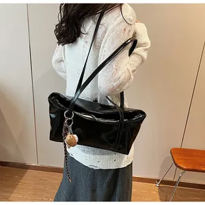 Detail of black glossy leather shoulder bag with a cute brown woven animal charm
