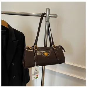 Details einer dunkelbraunen Handtasche aus Lackleder mit goldenem Dreiecksdekor und Trägern