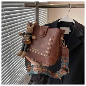 Détail macro du sac seau marron caramel avec rivets dorés et bandoulière tissée