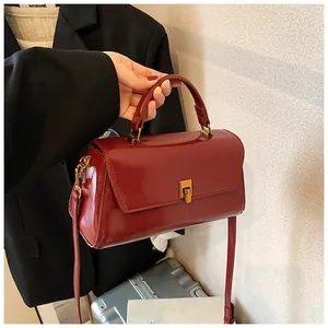 Close-up of glossy wine red patent leather mini bag with elegant gold metal clasp