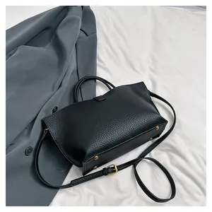 Close-up of black lychee grain leather tote with gold hardware and protective feet