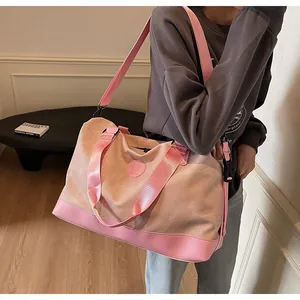 Gros plan du sac de voyage rose montrant la texture en toile et les détails en cuir